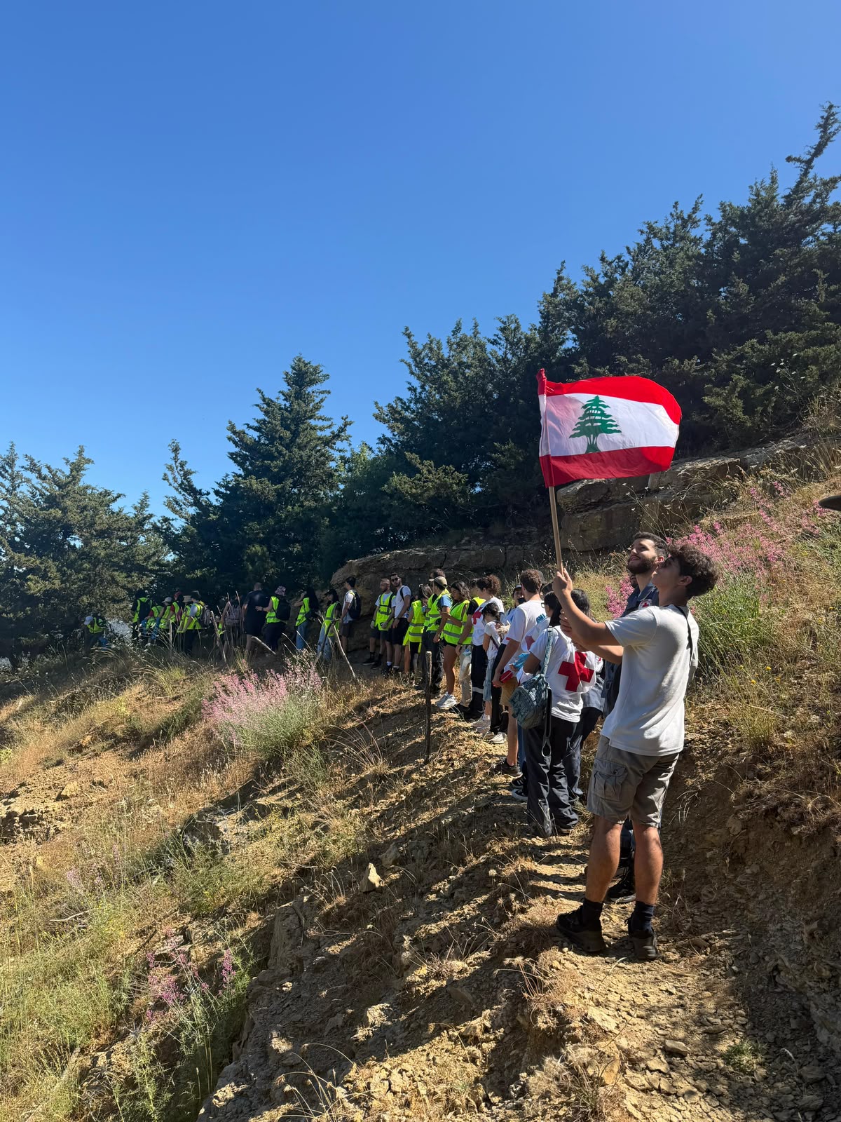 Volunteers on a mountain trail with the Lebanese flag during the Qornet el Hamra eco-hike